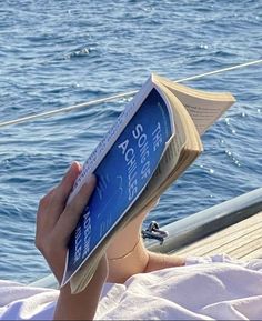 a person reading a book while sitting on a boat