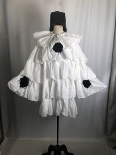 a white dress with black ruffles is on a mannequin headdress