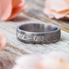 the wedding band is made from wood and has silver inlaying it, along with pink flowers