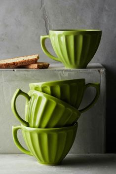 three green cups stacked on top of each other next to a piece of toasted bread