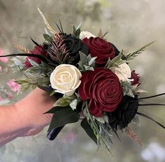 a person holding a bouquet of flowers in their hand with pink, red and white flowers