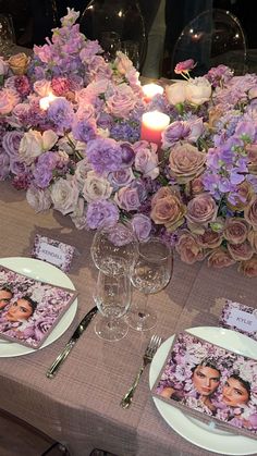 the table is set with purple flowers and place settings for two people to sit at