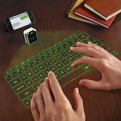 a person using a wireless keyboard on a wooden table with other electronic devices and notebooks