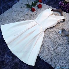 a white dress laying on top of a rug next to some shoes and red roses