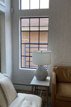 a living room with a couch, table and lamp next to a large open window