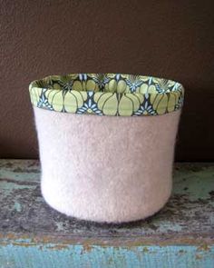 a white and green flower pot sitting on top of a wooden table next to a brown wall