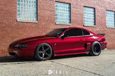 a red car parked in front of a brick building