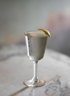 a close up of a glass on a table with a lemon wedge in the middle