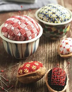 several different types of buttons in small bowls on a wooden table with pins and needles