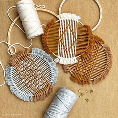 three pieces of woven macrame sitting on top of a table next to yarn