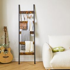 a living room with a white chair and a wooden ladder in the corner next to a guitar