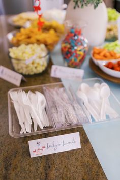 there are many forks and spoons on the table with name tags in plastic containers