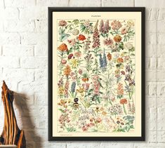 a white wall with flowers on it next to a wooden shelf and a brick wall