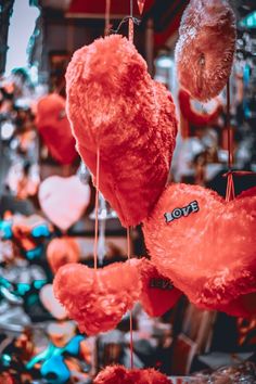 red teddy bears hanging from strings in front of a christmas tree with hearts on it