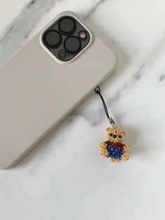 a cell phone with a teddy bear keychain attached to it's back