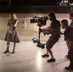 a group of people standing around each other in front of a brick wall and camera