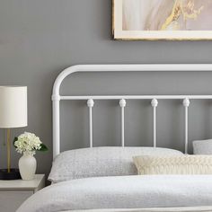 a white headboard and foot board in a gray room with a painting on the wall