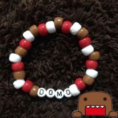 a red, white and brown beaded bracelet with the word domo on it