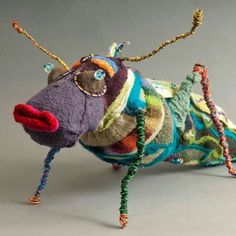 an animal made out of yarn and beads on a gray surface with one leg up