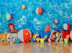 there are many beach balls and toys on the floor in front of a blue wall