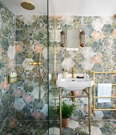 a bathroom with hexagonal tiles on the wall and a gold faucet