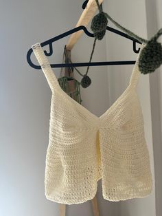 a crocheted top hanging on a clothes rack next to a wooden hanger