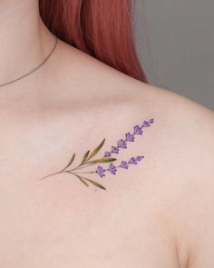 a close up of a woman's chest with purple flowers on her left shoulder