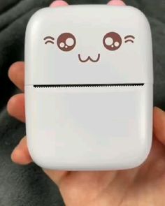 a person holding up a white case with eyes and nose drawn on the back of it