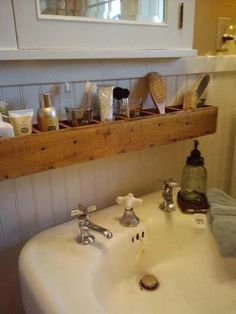 a white sink sitting under a window next to a wooden shelf filled with soap and toothbrushes