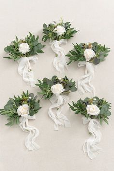 white flowers and greenery are arranged in the shape of ribbons on a gray background