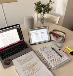 an open laptop computer sitting on top of a table next to a notebook and pen