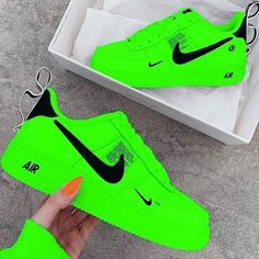 someone is holding up a neon green nike air force shoe in front of a box