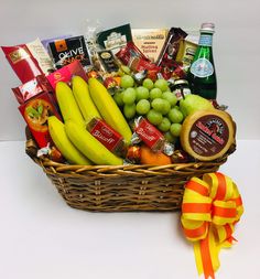 a basket filled with fruit and snacks next to a yellow ribbon on a white table