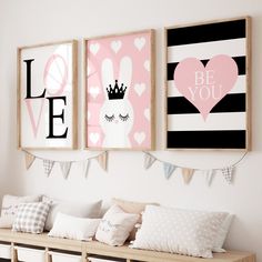 three framed pictures hang on the wall above a bench with pillows and pillow cases in front of them