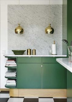 a kitchen with green cabinetry and gold fixtures on the wall, along with marble counter tops