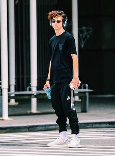 a young man wearing headphones while walking across a street