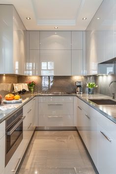 a kitchen with white cupboards and stainless steel appliances in the center, along with marble counter tops