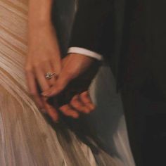 a close up of two people holding each other's hands and wearing wedding rings