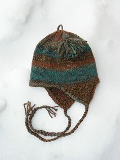 a knitted hat is laying in the snow on top of it's string