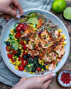 someone is holding a fork over a plate of chicken, rice and veggies