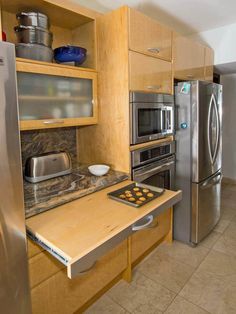 a kitchen with stainless steel appliances and wooden cabinetry is pictured in this image, there are cookies on the counter