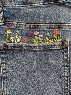 the back pocket of a pair of jeans with embroidered flowers