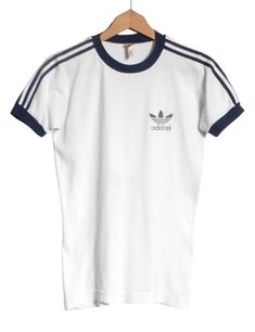 Vintage 1970's Adidas t shirt in a white colour. Trefoil on the chest and trademark three stripes down the sleeves. Made from a cotton polyester blend.  Condition: Excellent vintage condition. Bust: 34in Length: 25in More vintage clothing on our website www.brickvintage.com Affordable Trendy Adidas T-shirt, Vintage Adidas Shirt, Classic White Tops With Three Stripes, Classic White Top With Three Stripes, Retro Three Stripes T-shirt For Streetwear, Retro Cotton T-shirt With Three Stripes, Vintage White Crew Neck T-shirt, Vintage White T-shirt With Screen Print, Vintage White Cotton T-shirt