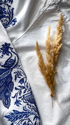 two dried plants sitting on top of a blue and white cloth covered tablecloths