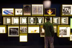 a man standing in front of a wall with many pictures on it that say innovate