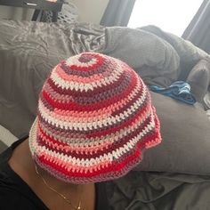 a woman wearing a red, white and grey crocheted hat