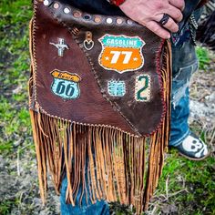 a close up of a person holding a bag with stickers on it and fringe