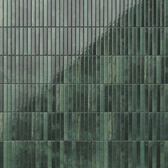 the side of a tall building with many vertical lines on it's sides and trees in the background