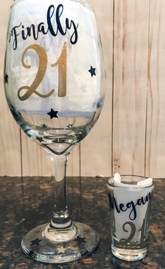 a wine glass with the number 21 on it next to a shot glass that says finally 21st