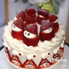 a white cake with strawberries on top and frosting in the shape of santa claus